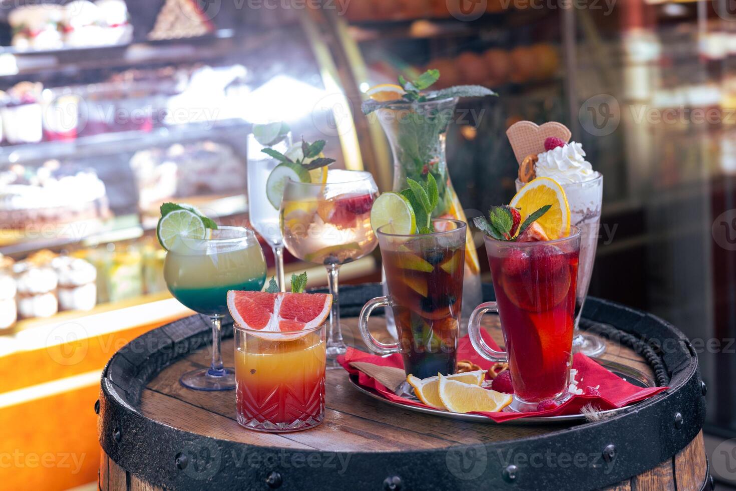 Colorful assortment of refreshing cocktails displayed on a rustic barrel outside a cafe in spring photo