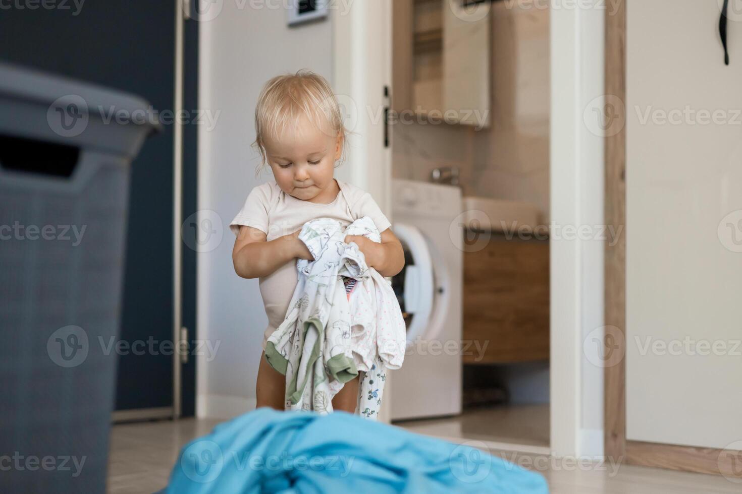 small caucasian child daughter helps mother with a laundry photo