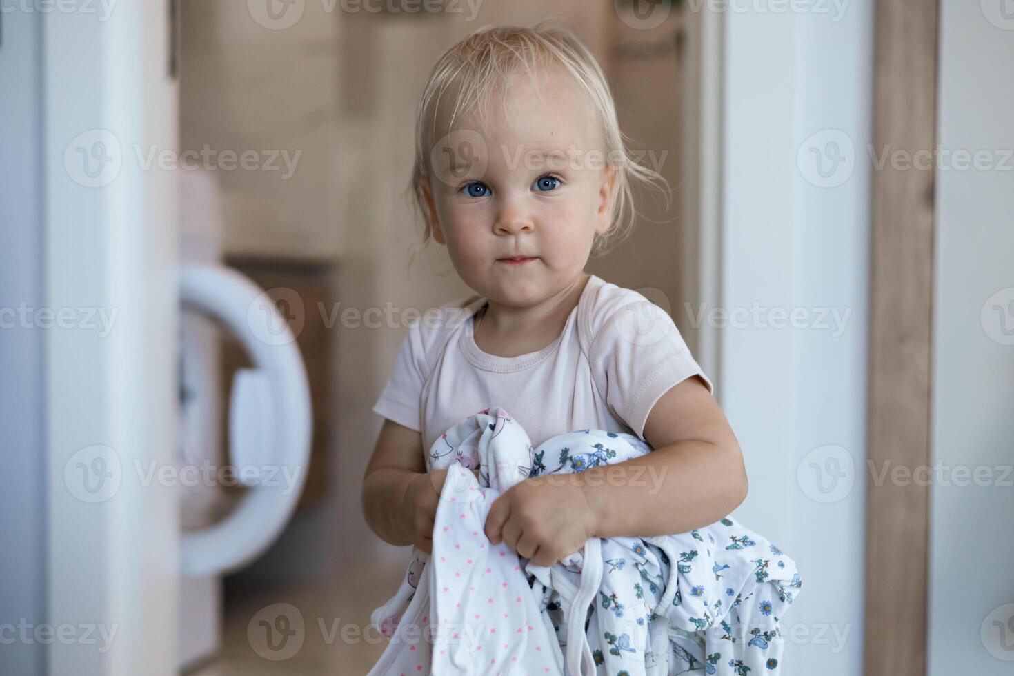 small caucasian child daughter helps mother with a laundry photo