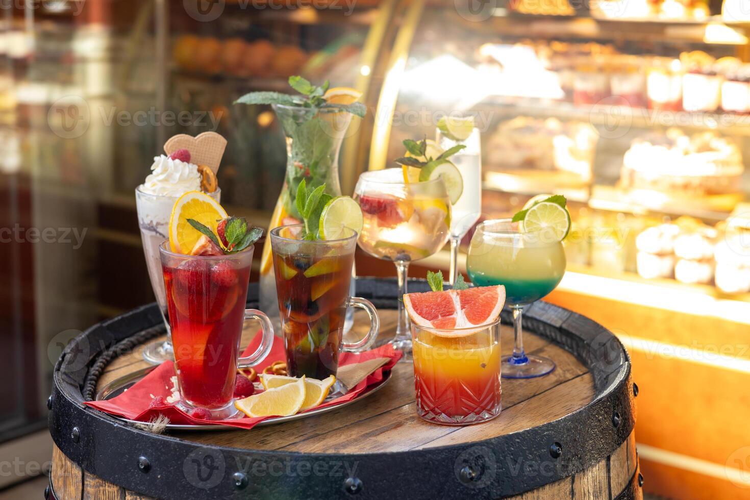 Colorful assortment of refreshing cocktails displayed on a rustic barrel outside a cafe in spring photo