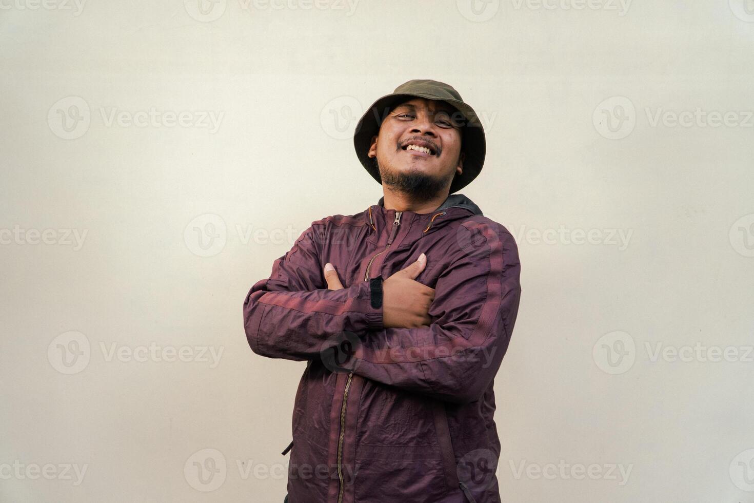 Half body of adult Asian man with beard and mustache is posing in various styles. Mature macho man wearing adventure outfit with jacket and bucket hat isolated on beige background. photo