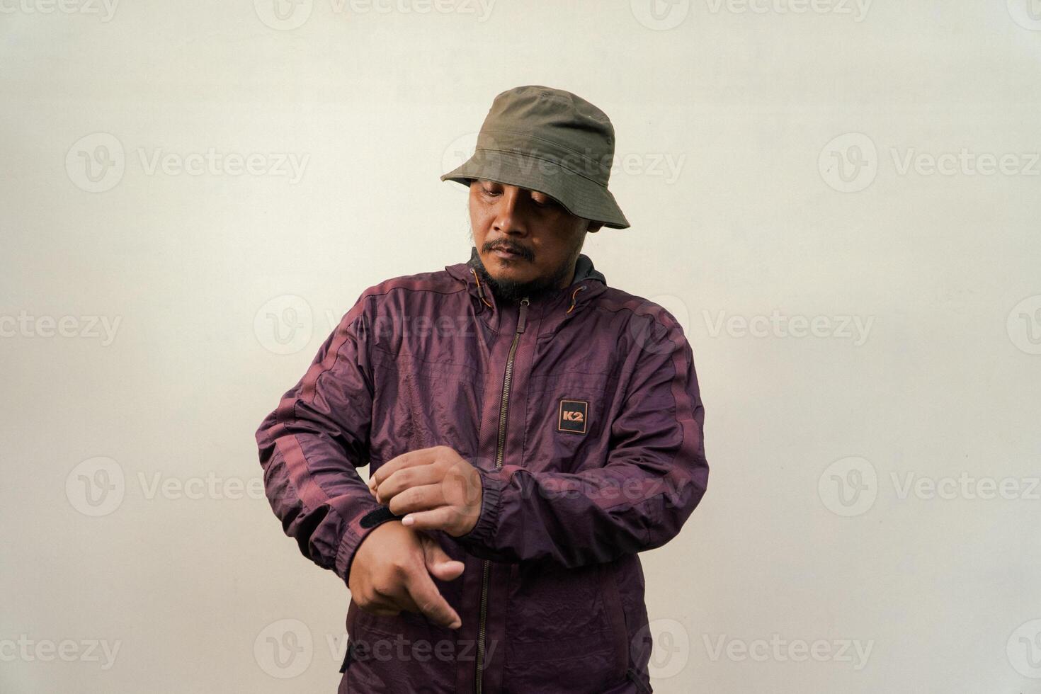 Half body of adult Asian man with beard and mustache is posing in various styles. Mature macho man wearing adventure outfit with jacket and bucket hat isolated on beige background. photo