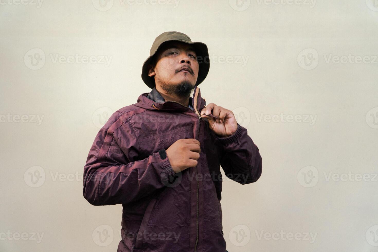 Half body of adult Asian man with beard and mustache is posing in various styles. Mature macho man wearing adventure outfit with jacket and bucket hat isolated on beige background. photo