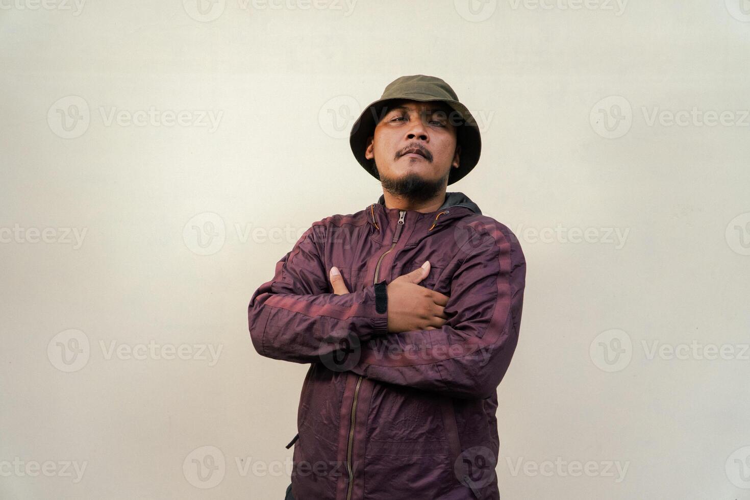 Half body of adult Asian man with beard and mustache is posing in various styles. Mature macho man wearing adventure outfit with jacket and bucket hat isolated on beige background. photo