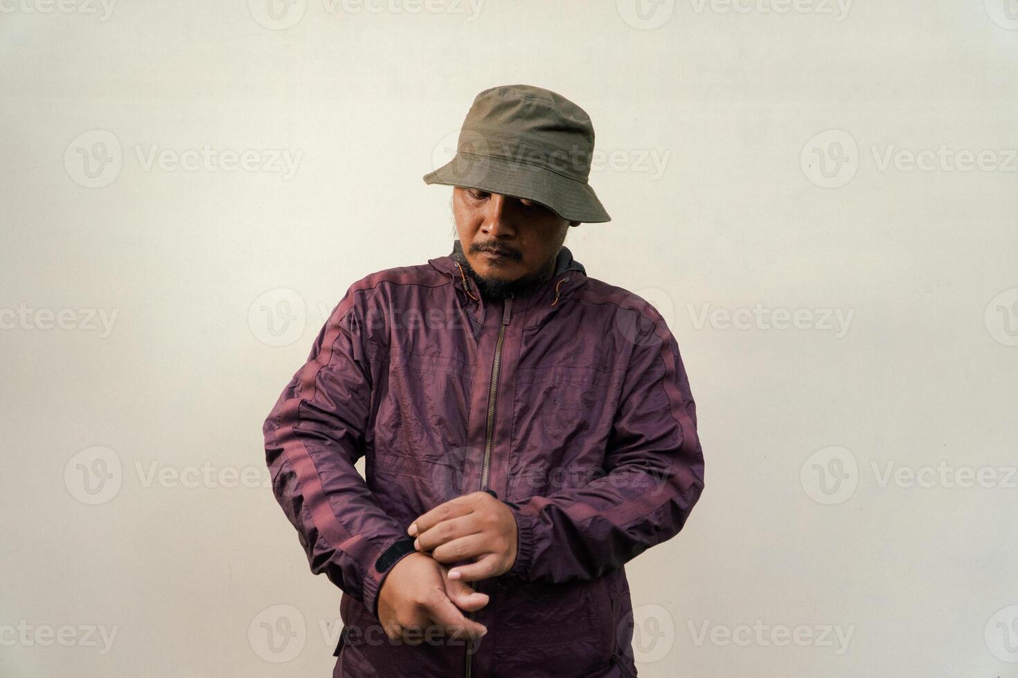 Half body of adult Asian man with beard and mustache is posing in various styles. Mature macho man wearing adventure outfit with jacket and bucket hat isolated on beige background. photo