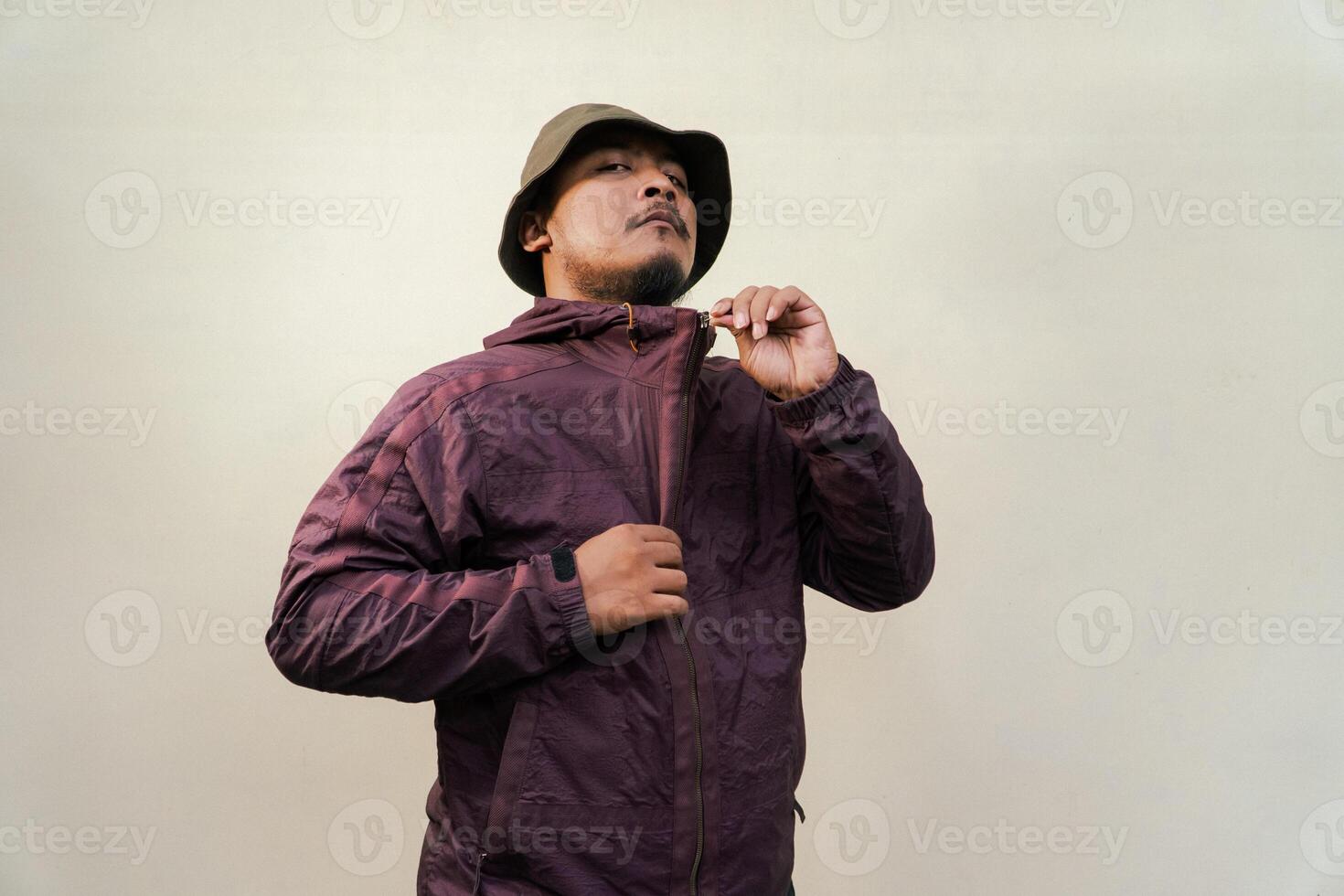 Half body of adult Asian man with beard and mustache is posing in various styles. Mature macho man wearing adventure outfit with jacket and bucket hat isolated on beige background. photo