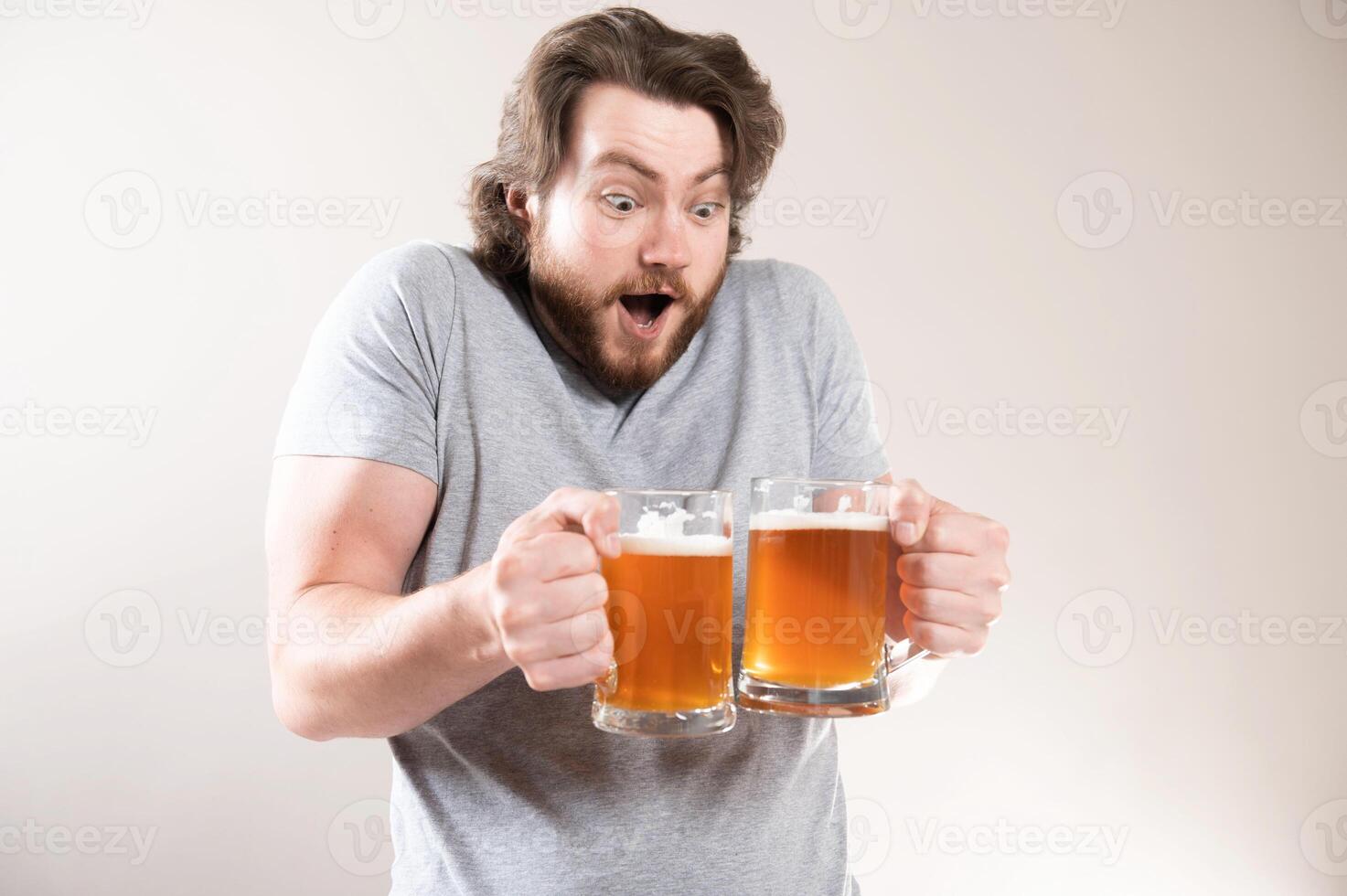 A man with muscular arms in a gray t-shirt is holding two beer mugs, a man and a beer photo