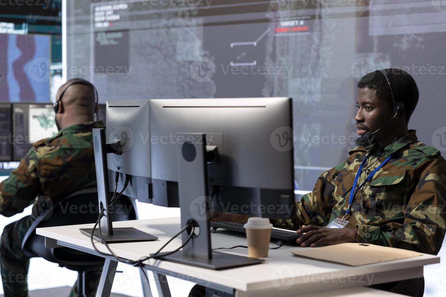 Government expert working in a high tech command post to gather intelligence from surveillance cctv systems. Soldier analyzing real time data and transmitting crucial field information for defense. photo