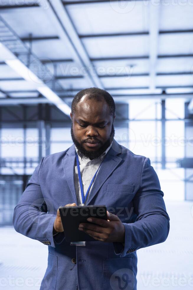 Data center technician ensuring safety and security of database using tablet. Server hub employee preventing unauthorized access and suspicious activities within the network posing risks for business photo