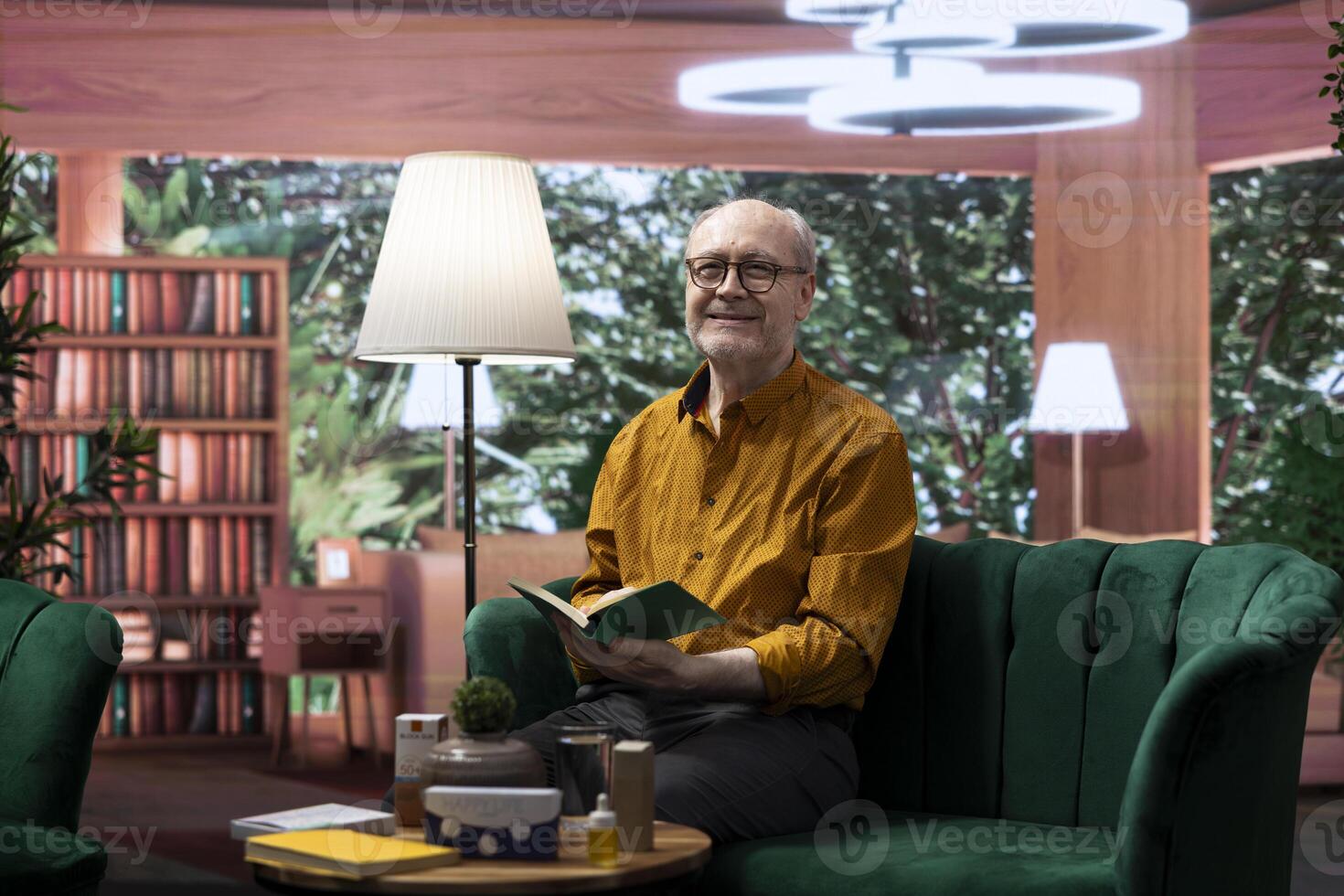 Elderly man reading a book sitting alone in his lounge area at home, relaxing and feeling good with free time. Person with an intellectual hobby, passionate about literature and lecture. photo