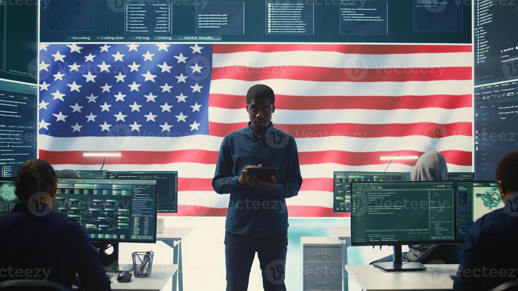 Cybersecurity expert working in a governmental hacking room with the American flag shown on big screen. Safeguarding data protection and doing cyber threat analysis in a high tech office. Camera B. photo