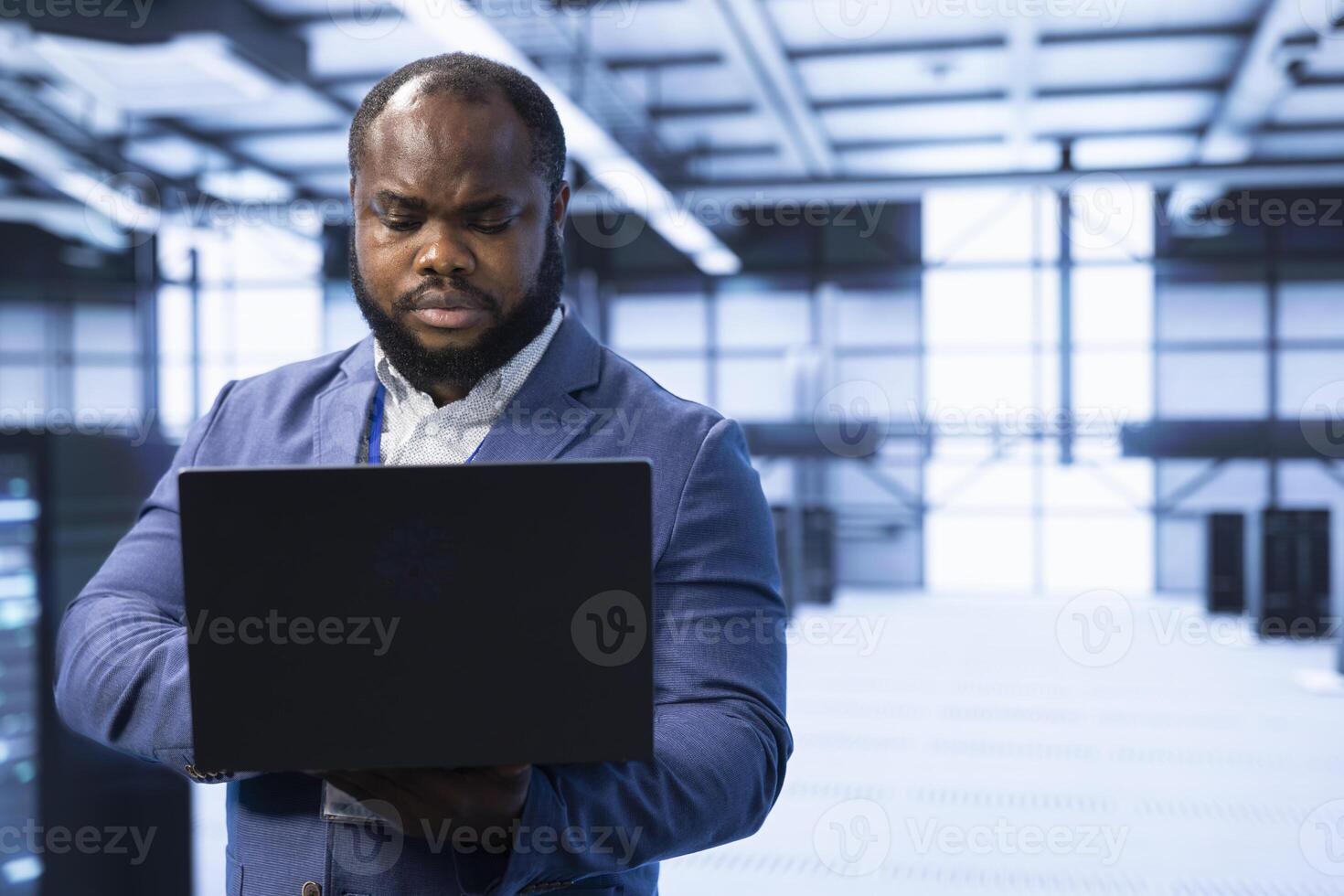 Engineer in server room using laptop to implement and maintain security measures, protecting systems from unauthorized access. Data center worker doing hardware installation using notebook photo