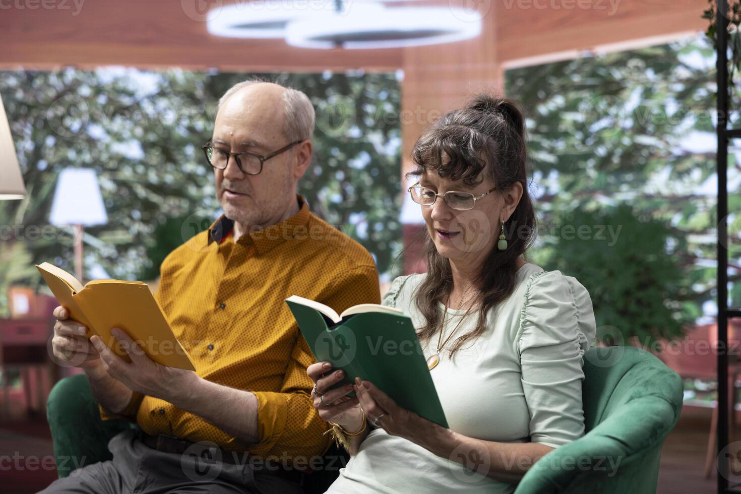 Senior people reading a literature book relaxing together at home, sitting on the couch and enjoying lecture. Feeling good with free time for leisure during retirement, companionship. photo