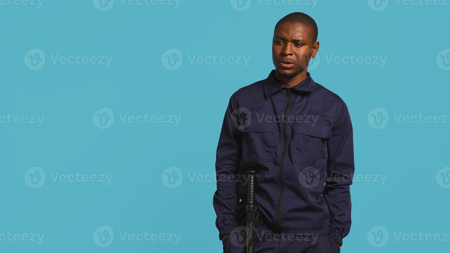 Portrait of security guard looking around while overseeing premises. Private law enforcement worker doing surveillance job, inspecting location, studio backdrop, camera B photo