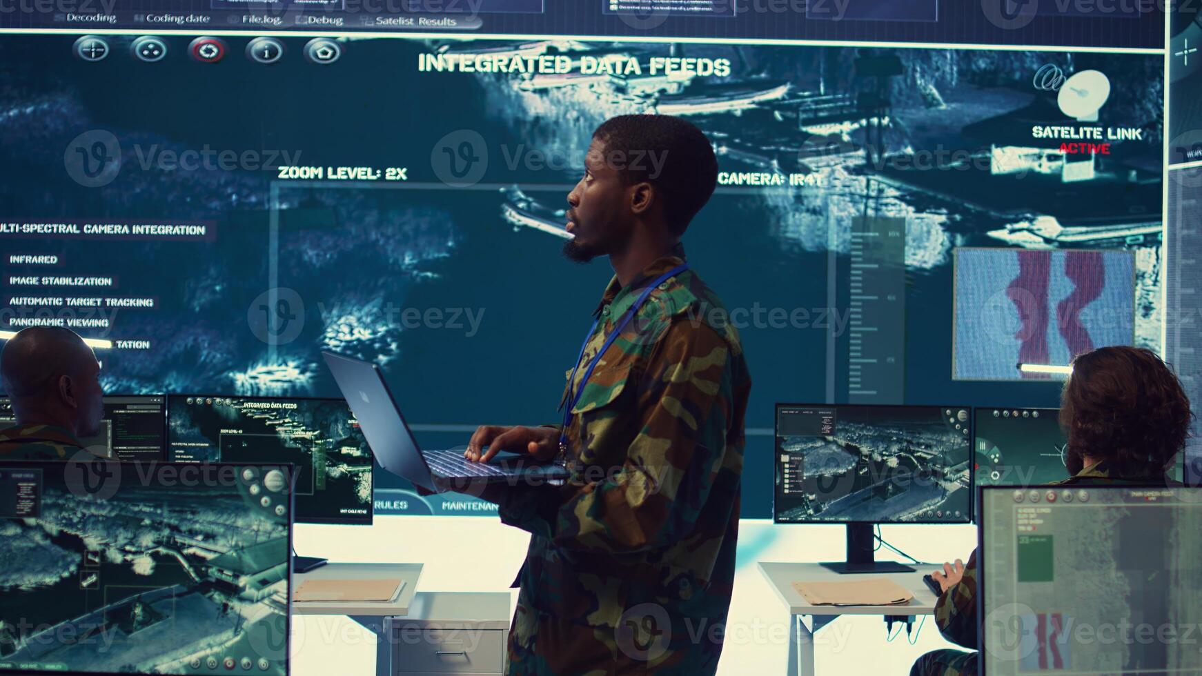 Army officer examines satellite radar footage to gather intelligence for a new mission, operating in military headquarters power base with his crew. Federal agency officers in control room. Camera B. photo