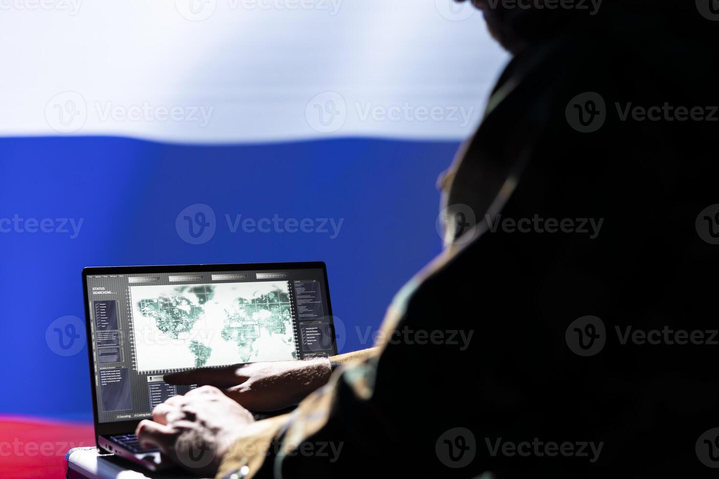 Russian ex KGB FSB operative engaged in surveillance mission using laptop, looking at world map. Intelligence officer isolated over Russia flag working for Kremlin regime monitoring zone of interest photo