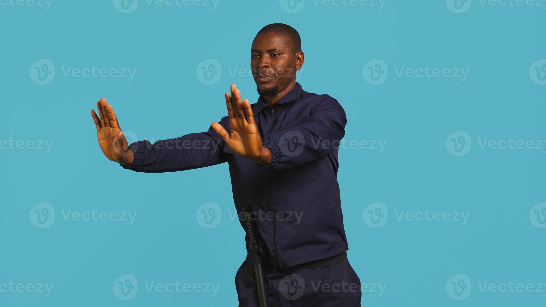 Portrait of security agent doing crowd control, securing assigned post, studio background. African american guardian pushing back unwanted trespassers, handling security breaches, camera B photo
