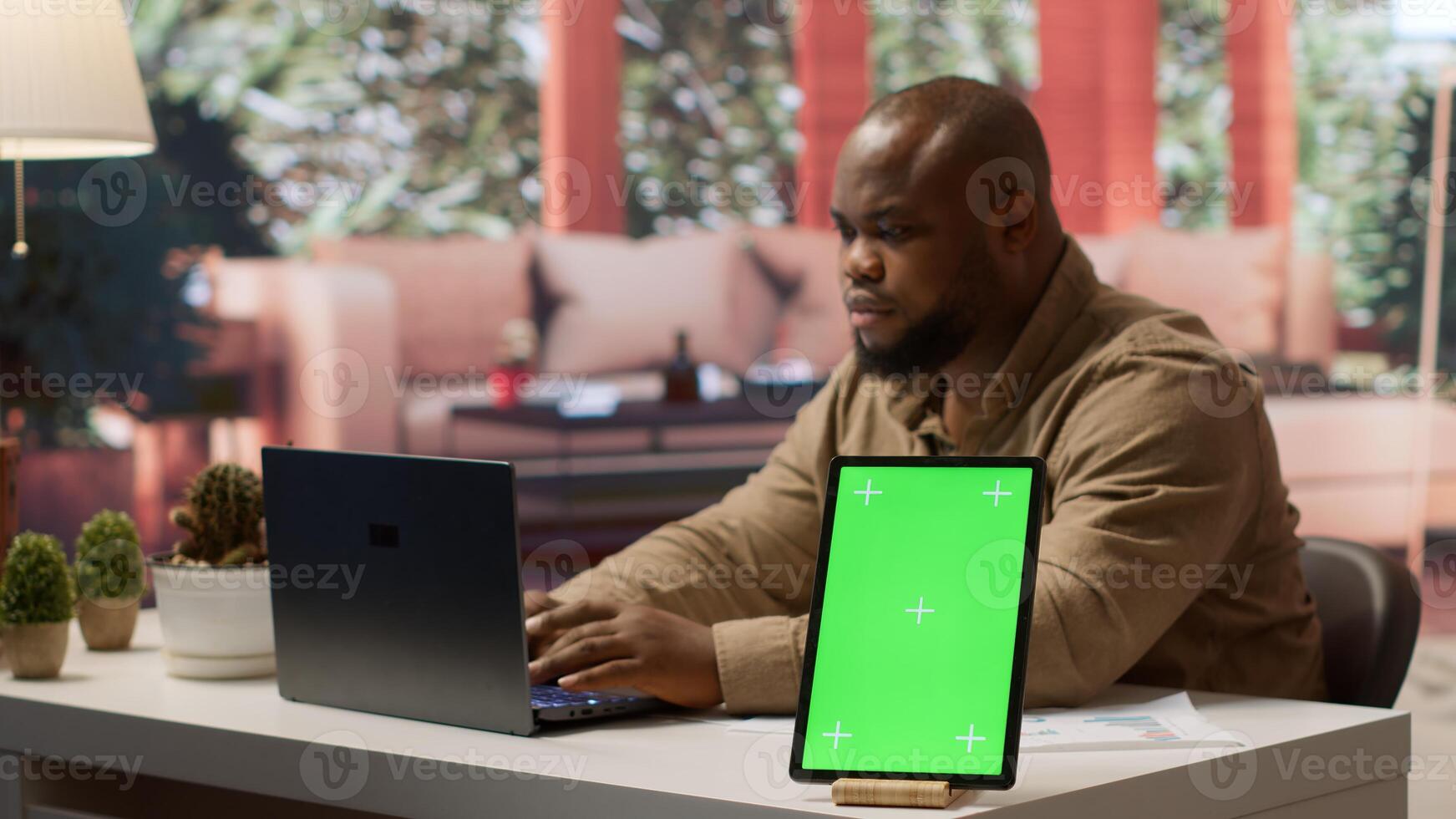 Business owner manages financial plans next to a mockup display on tablet, using annual sales analytics and reports to increase the profit. Entrepreneur does budget analysis at home. Camera A. photo