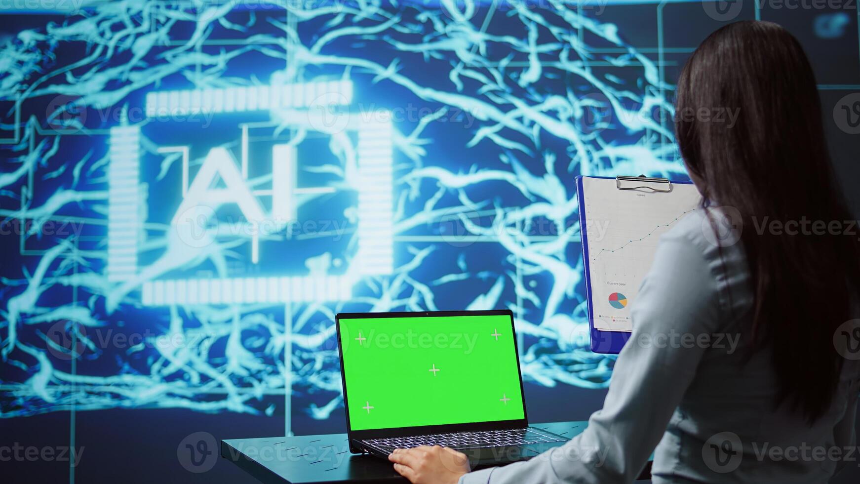 Startup employee looking over charts, using AI software on green screen laptop to take data driven decisions. Indian woman developing innovative artificial intelligence solutions for company, camera B photo
