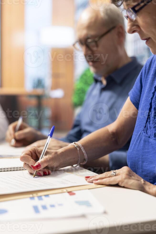 Middle aged person signing the agreement contract with the bank, ensuring their pension and life savings. Giving the signature on document for future financial security. Close up. photo