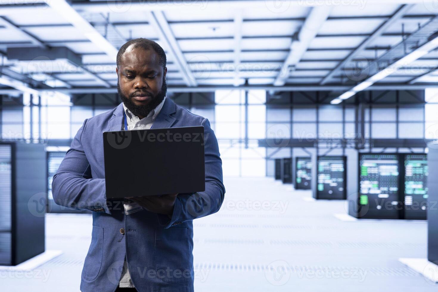 Technician walking in data center, monitoring system performance with laptop, identifying bottlenecks and implementing optimizations to improve efficiency. Server hub employee troubleshooting errors photo