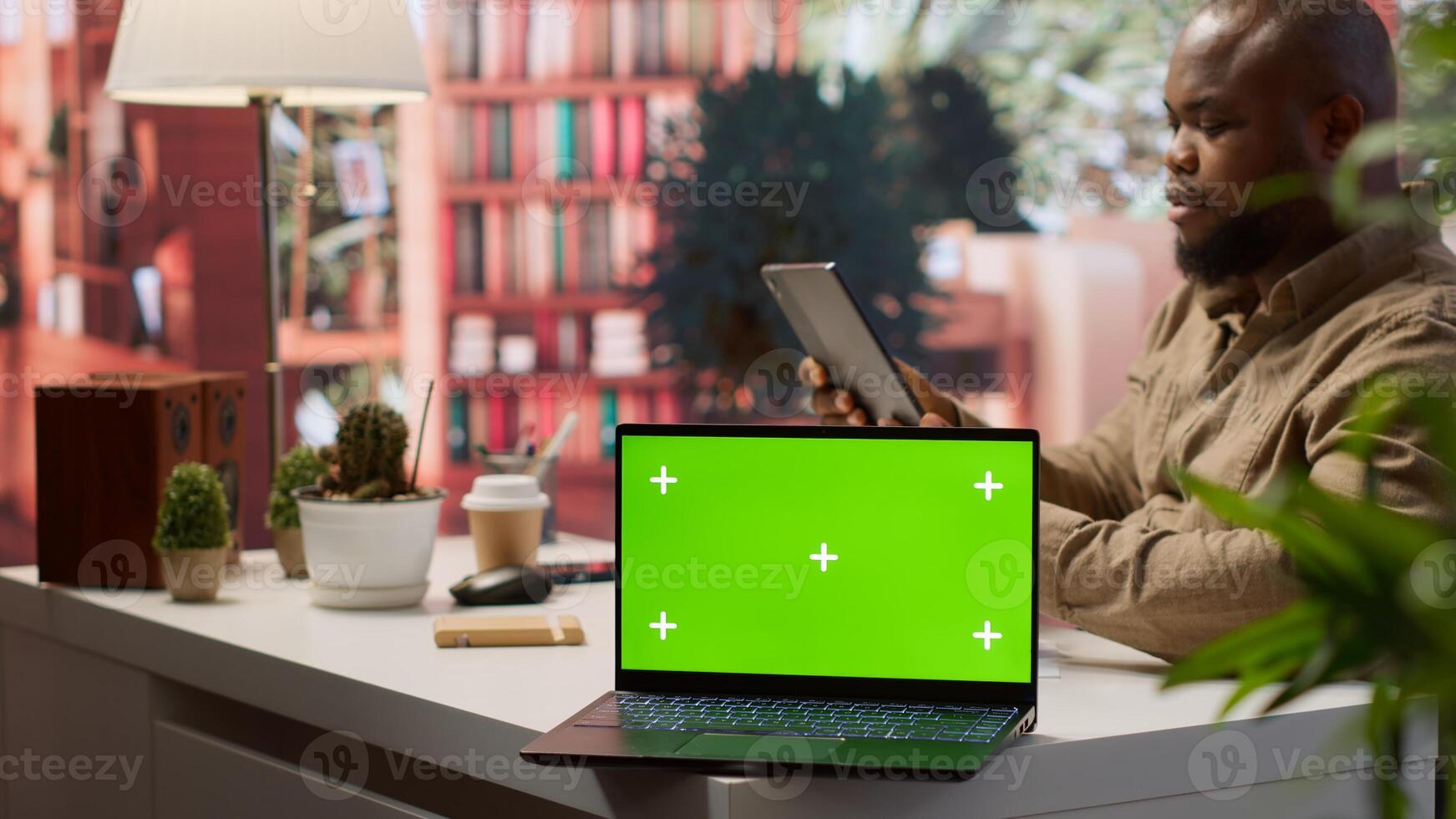 Small business owner works on finances plans next to a green screen, using annual sales analytics to increase startup profit. Entrepreneur does budget balance analysis at home desk. Camera A. photo