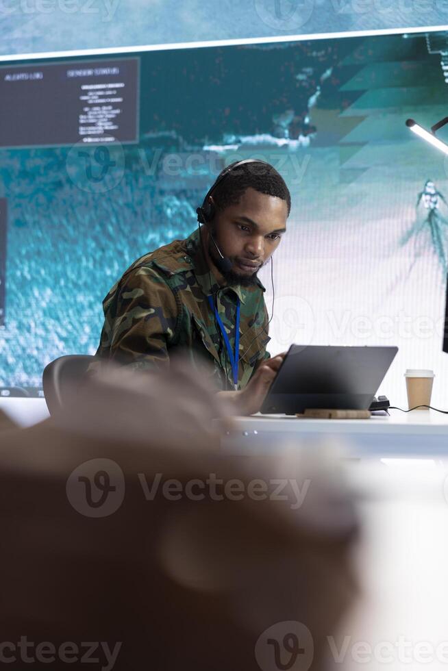 Military crew in a high tech control center working with real time data, supervising cctv satellite systems on a computer. Working with big screen in a command post for defense missions. photo