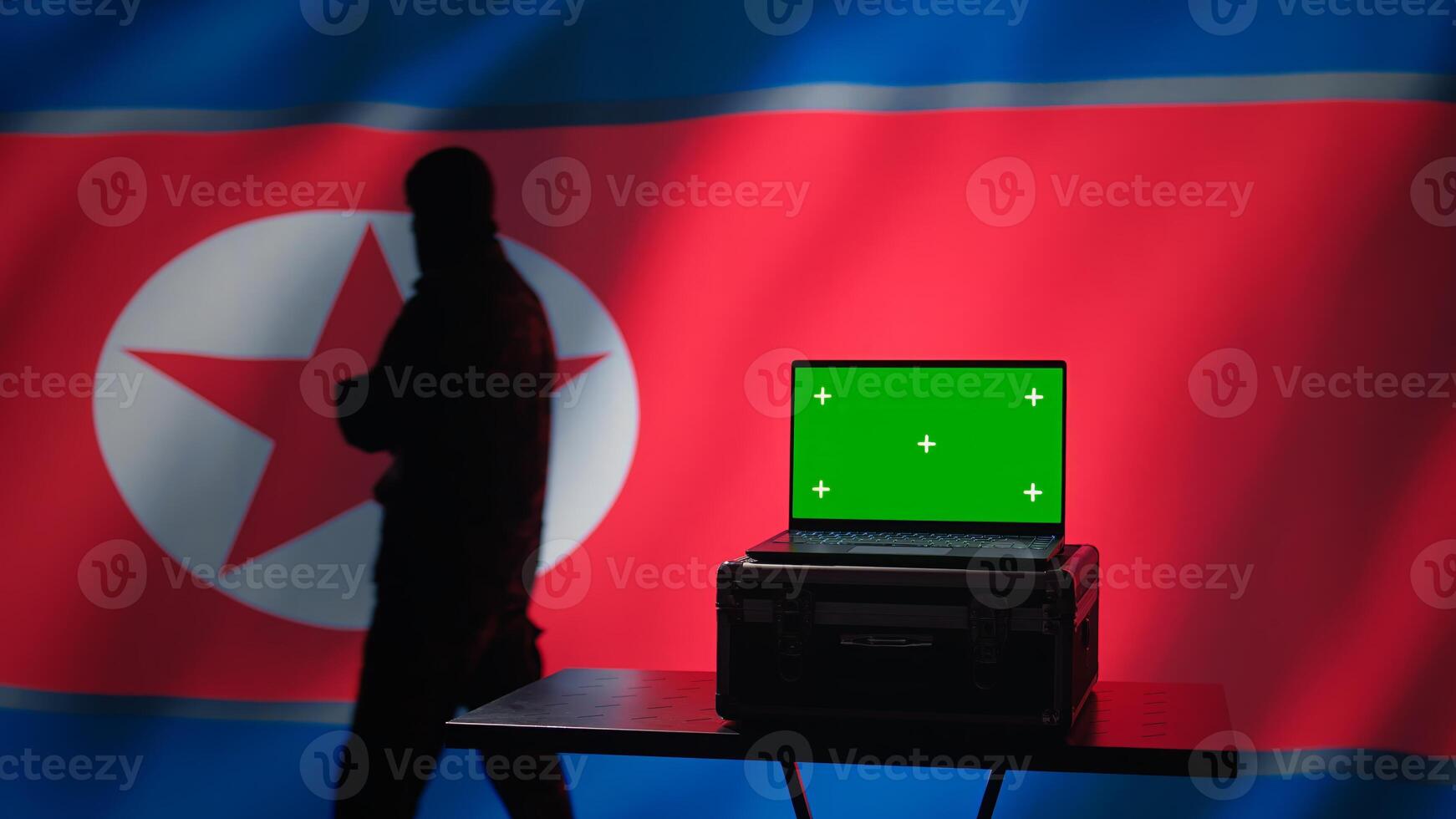 North Korea secret police agent uses mass propaganda tools on green screen laptop to influence population minds. Pyongyang regime commits PsyOp sabotage using mockup device, camera B photo