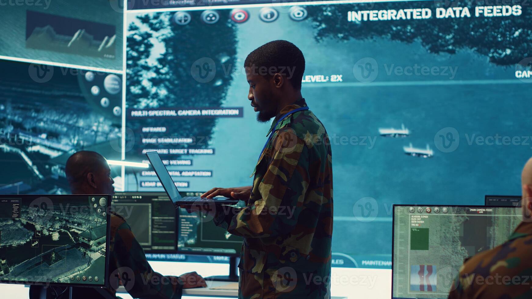Army officer examines satellite radar footage to gather intelligence for a new mission, operating in military headquarters power base with his crew. Federal agency officers in control room. Camera A. photo