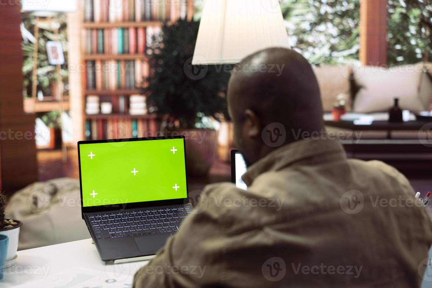 Businessman reviewing statistics reports next to an isolated mockup screen at home office, adviser calculating budget in order to expand the enterprise activity. Finance and economy. photo