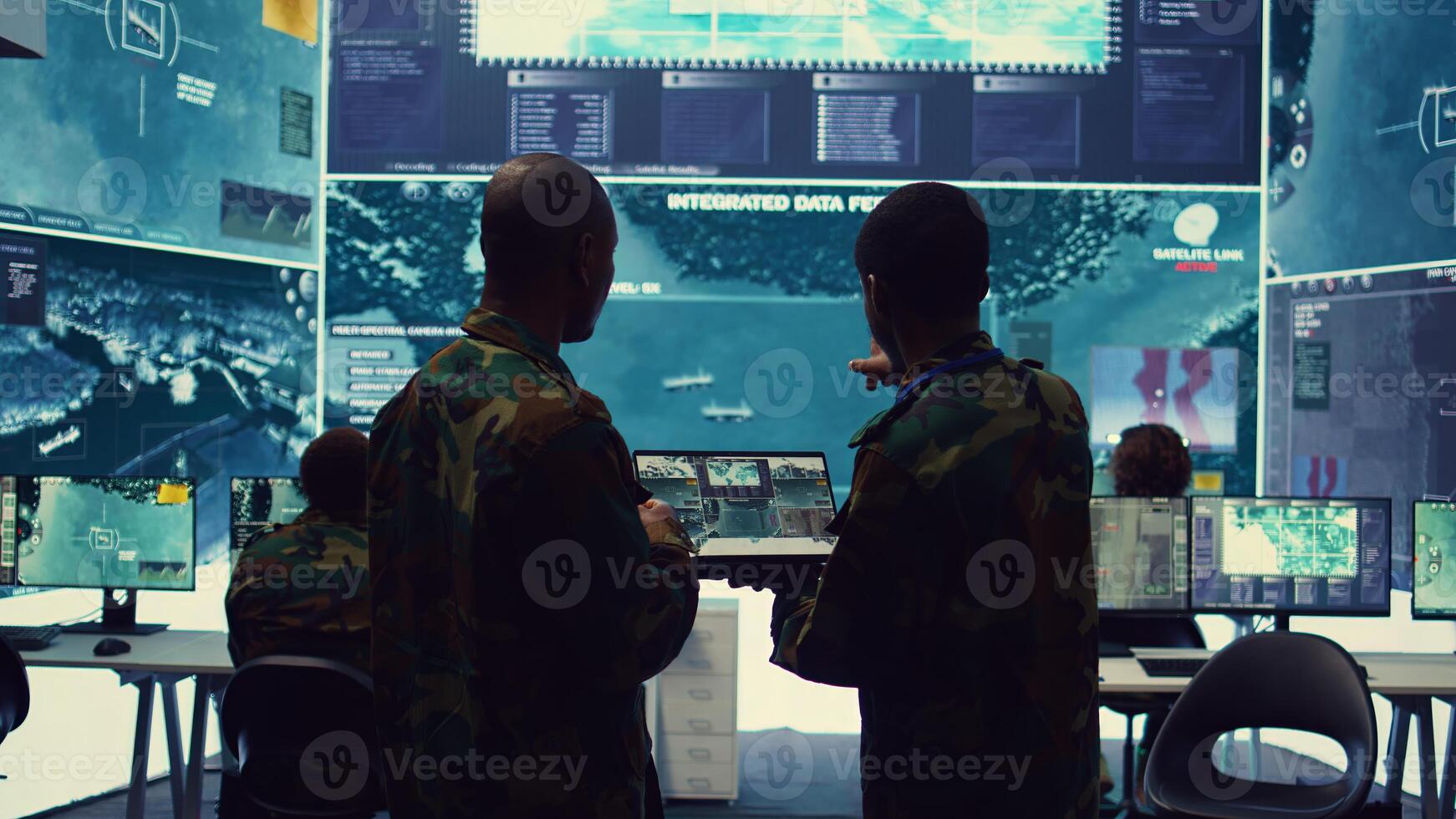 Intelligence analysts supervising and coordinating the big data analysis, processing tactical information to help the field troops. Officers monitoring real time warfare information. Camera B. photo