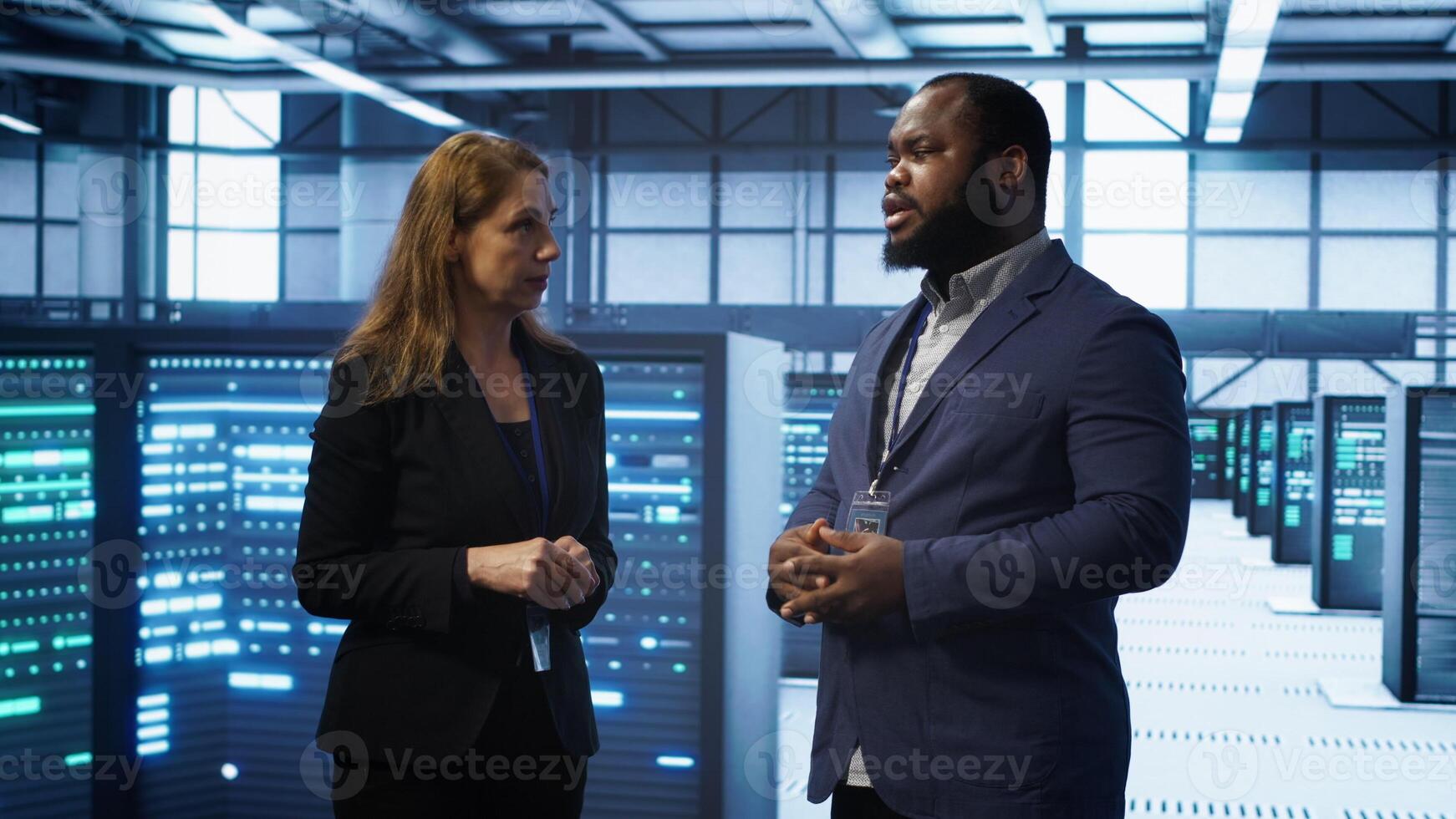 African american expert and coworker looking at holograms in data center, working together. Team members interacting with augmented reality AI visualization in server hub, camera A photo