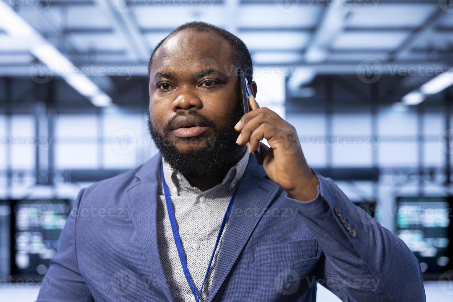 Team leader overseeing operations in modern data center, coordinating tasks during phone call. Close up of IT professional in server farm managing systems and communicating via smartphone photo