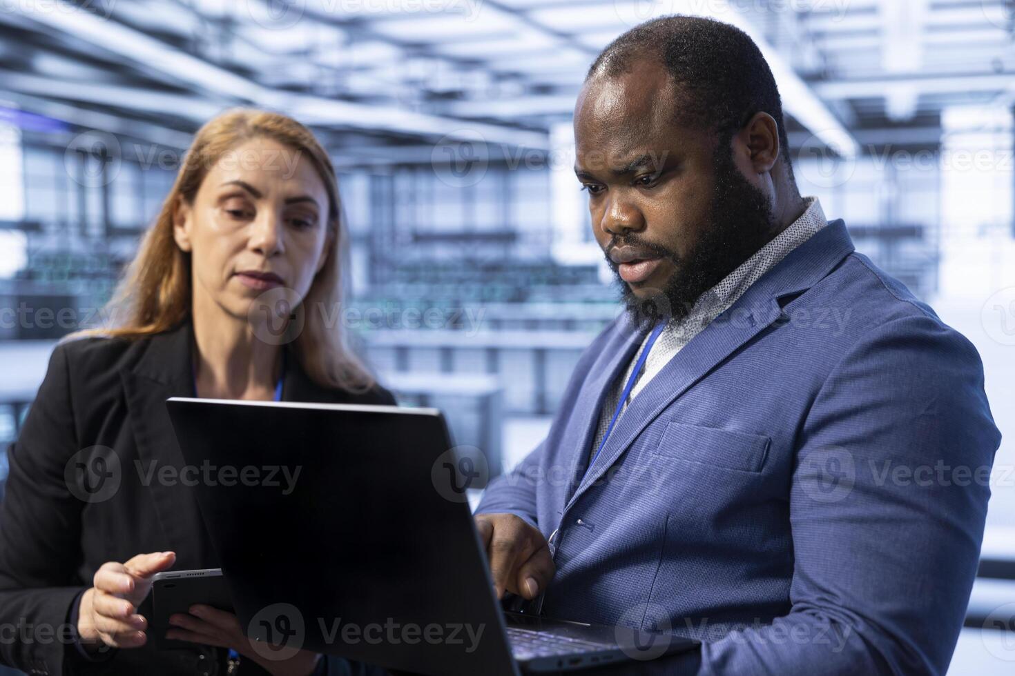 Teamworking admins in server room using laptop to implement and maintain security measures, protecting systems from unauthorized access. Data center IT professionals colleagues doing hardware upgrades photo