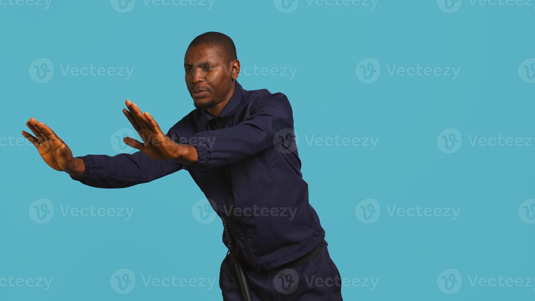 Portrait of security guard pushing back intruders while overseeing premises. Private law enforcement worker shoving away trespassers with hands, studio backdrop, camera B photo