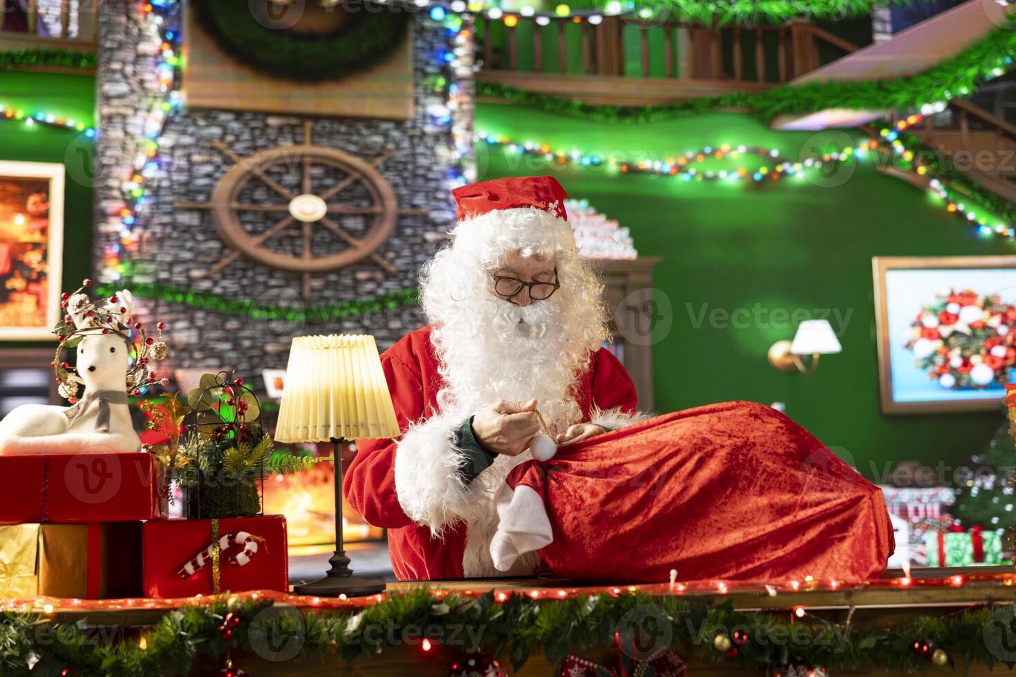 White bearded old man in costume tying his sack full of gifts, preparing for the journey around the world. Spreading the winter holiday spirit and surprising children, x mas tradition. photo