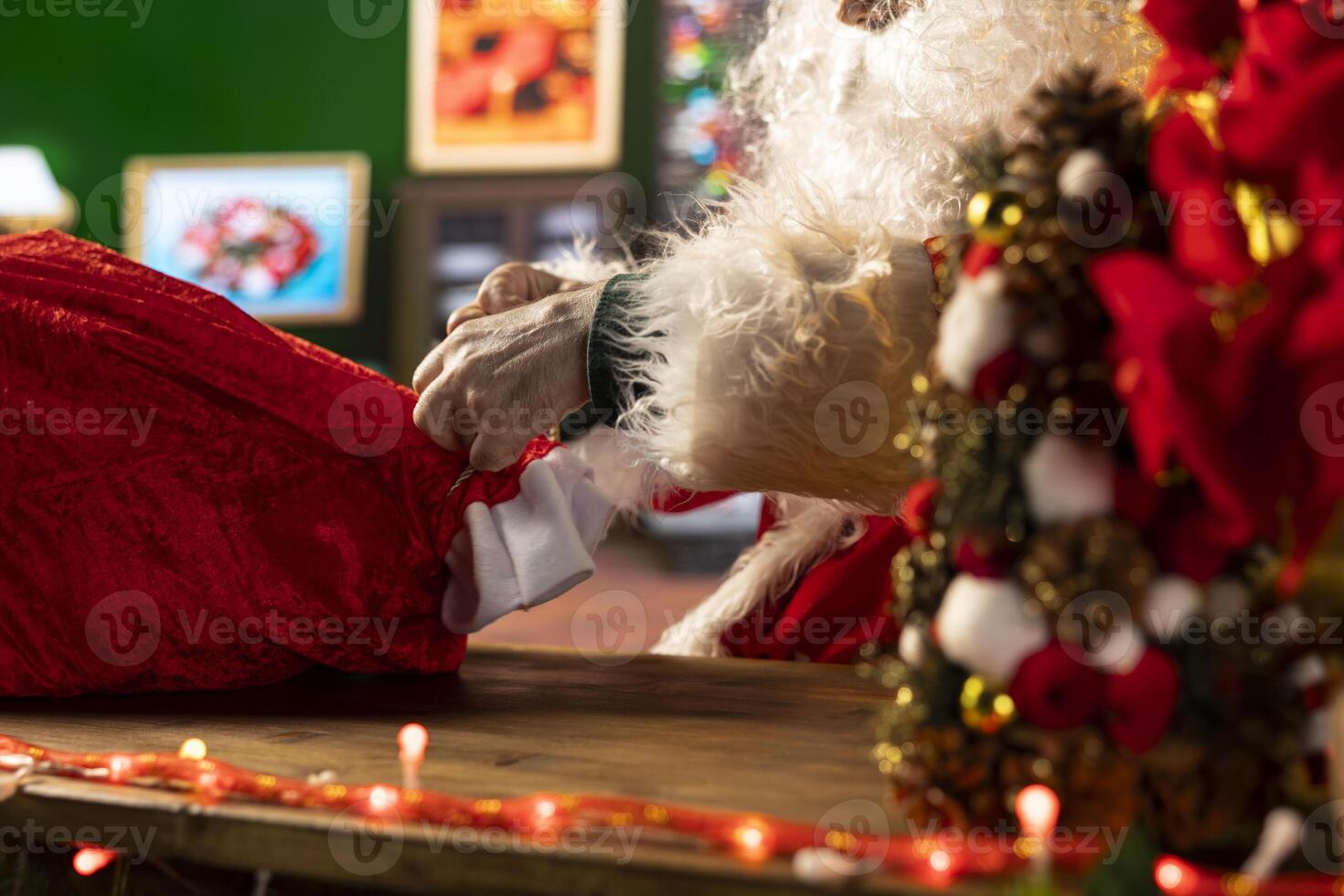 Old man Santa Claus preparing for the journey with his sack full of gifts, bringing presents to children on Christmas eve night. Festive Saint Nicholas in his North Pole log cabin, magic. Close up. photo