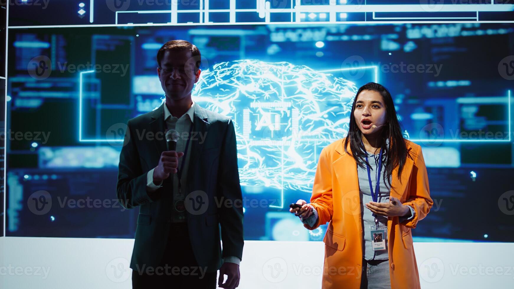 Tech specialists discussing during keynote summit presentation, exploring successful implementation of AI in driving forward businesses, sharing latest artificial intelligence innovations, camera B photo