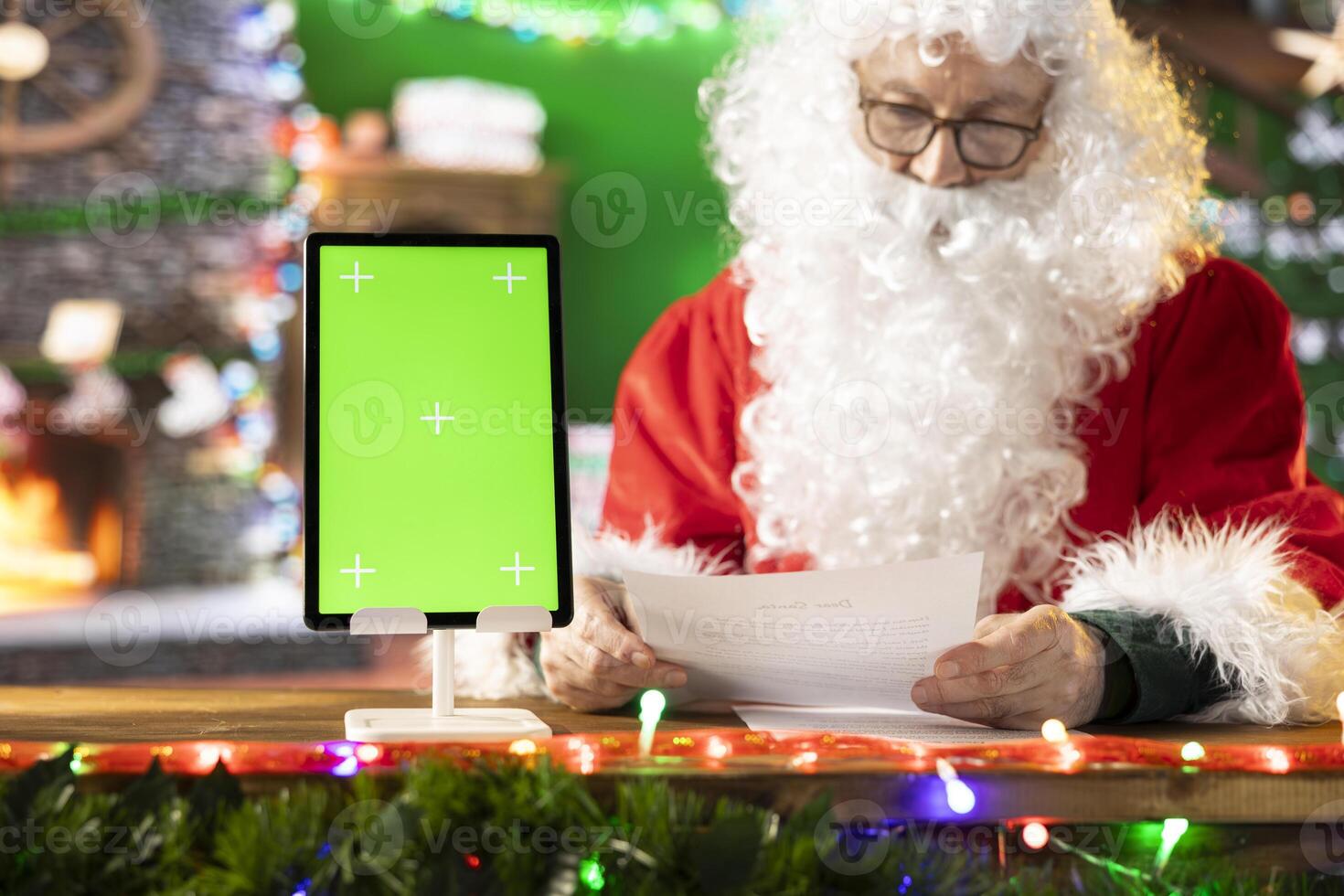 Santa Claus checking his naughty or nice list next to isolated mockup, preparing for his journey around the world to bring gifts on Christmas eve. Old man making children happy on x mas. photo