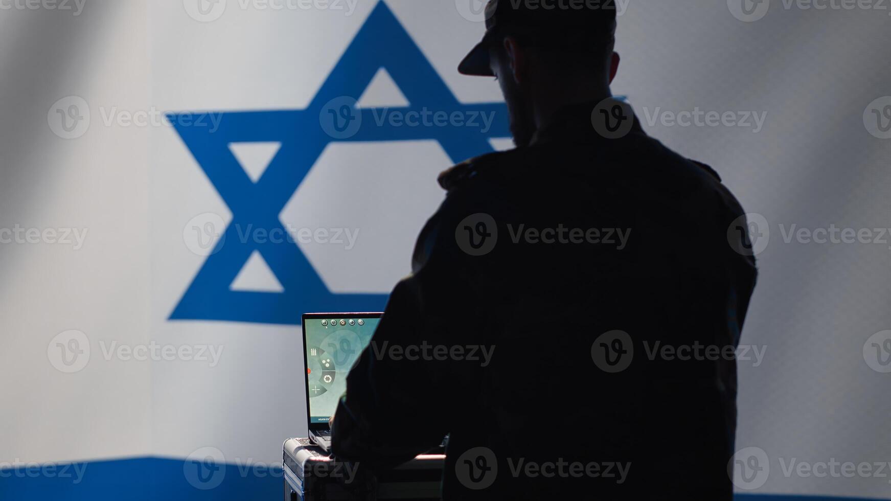 Iranian conscript in control room uses military tech to identify threats from enemies. Iran IDF army operator uses software on laptop to communicate information to generals on war front line, camera A photo