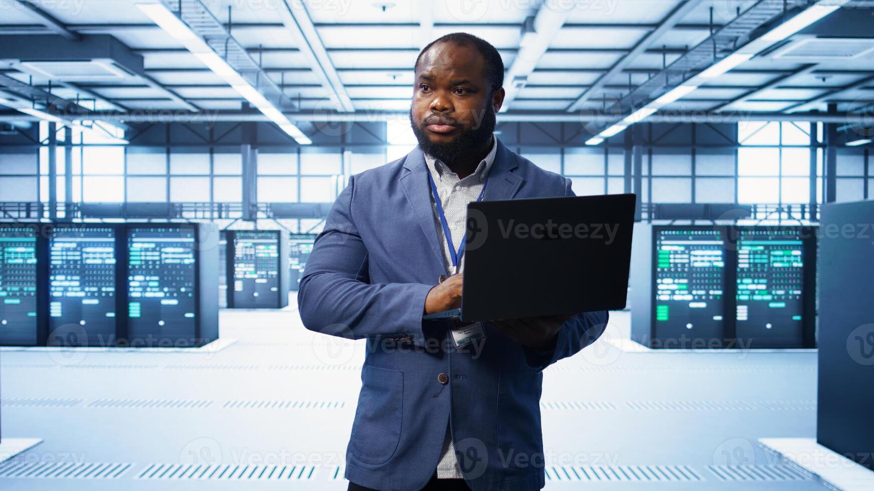 IT engineer working on laptop in modern data center, overseeing server operations, system maintenance,and cybersecurity protocols, ensuring optimal performance and data integrity, camera B photo