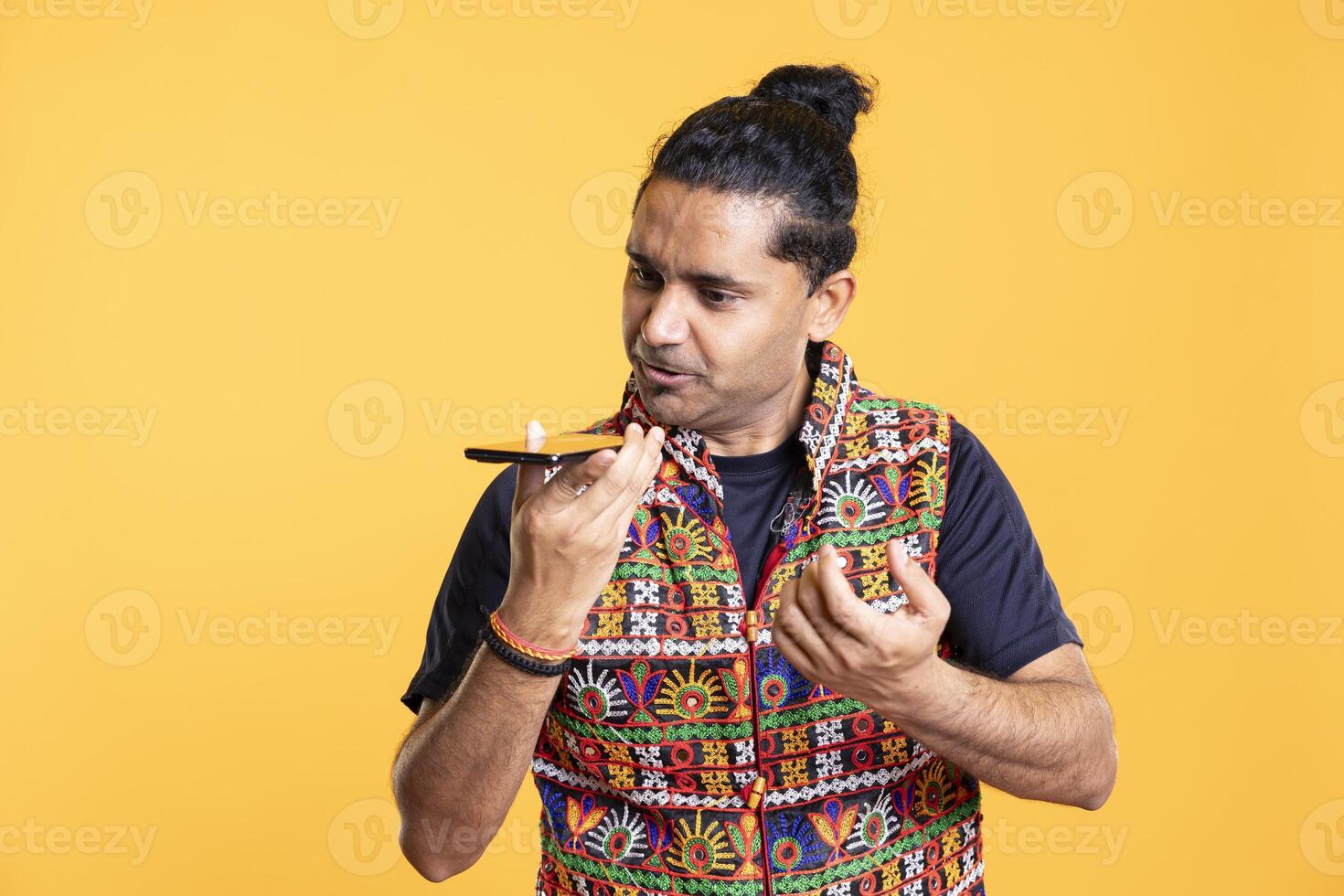 Man speaking in smartphone speaker, berating friend during argument in debacle, studio background. Dissatisfied person in disagreement with mate, having negative discussion during telephone call photo