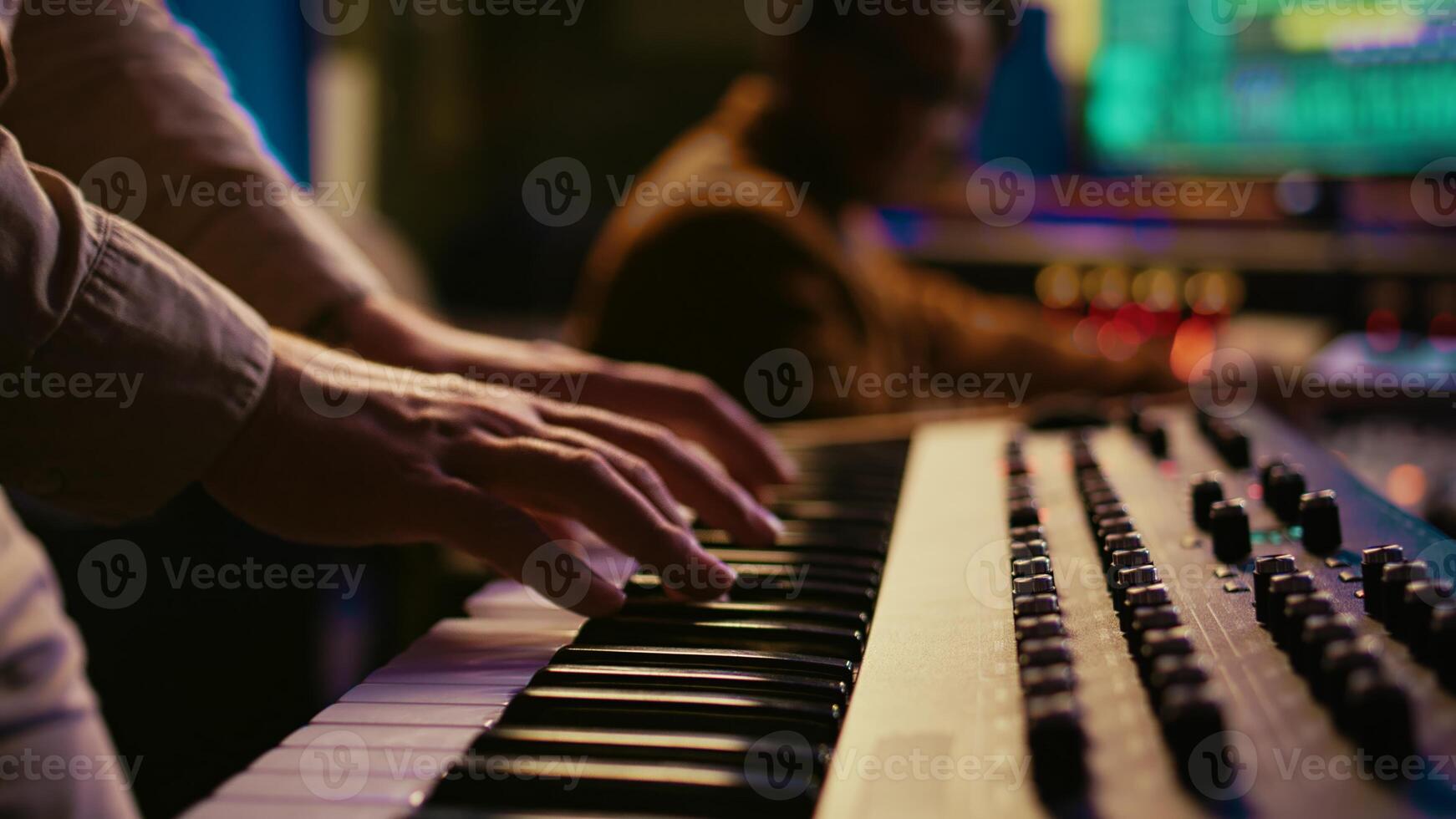 Musician composer playing midi controller synthesizer in professional studio, composing music on mixing console. Artist performing on piano electronic keyboard in control room. Camera B. photo