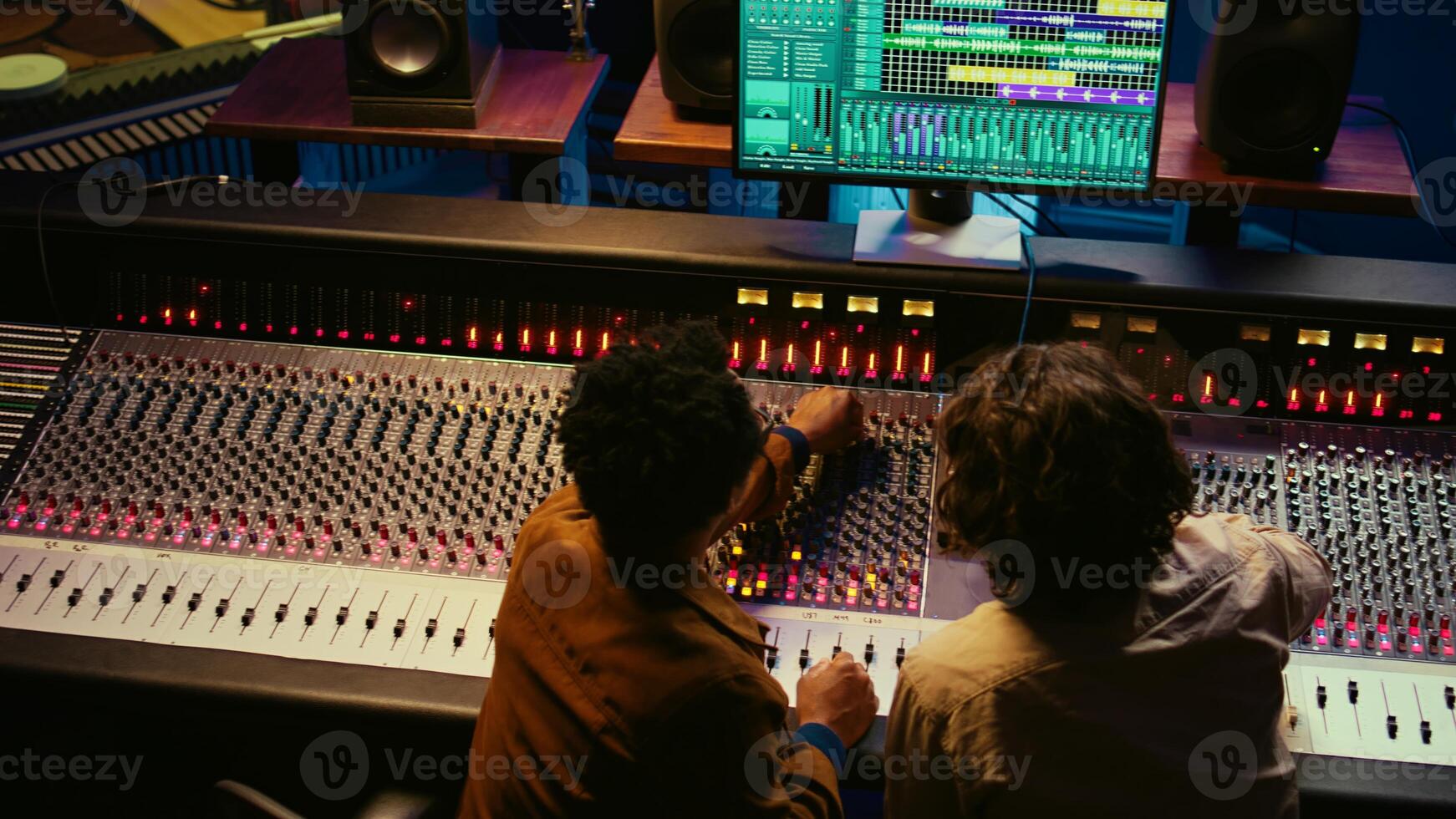 Musician and audio technician collaborating on mixing tracks to create a successful hit in professional studio. Team of experts listening to recordings and adding effects in post production. Camera B. photo