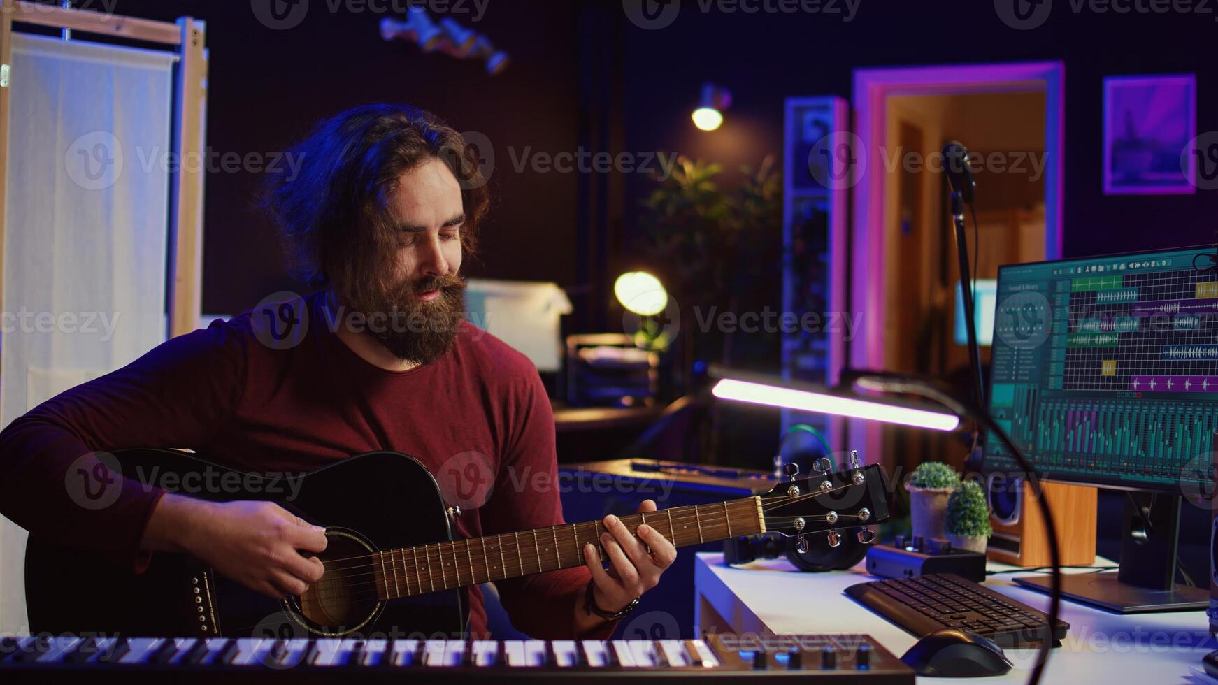 Portrait of artist recording tunes on daw software with his guitar, enjoying time in his home studio office. Audio engineer and musician creating new tracks, stereo electronic instruments. Camera B. photo