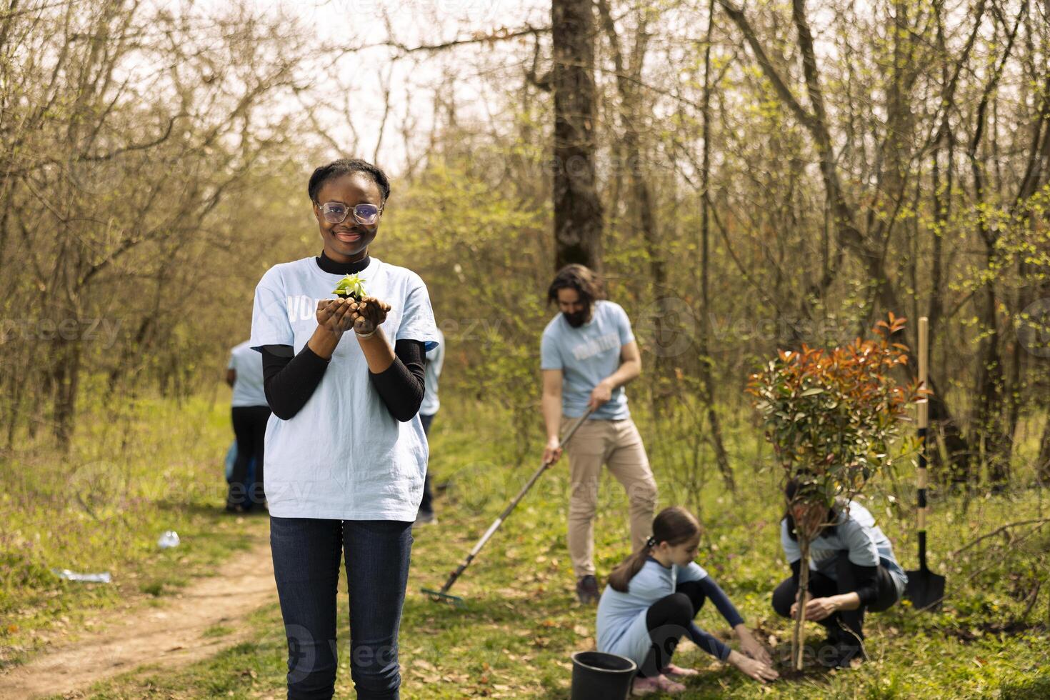 African american young girl advocating for nature protection by showing seedling in hands, growing small trees in organic soil for future generations. Volunteer preserving forest environment. photo