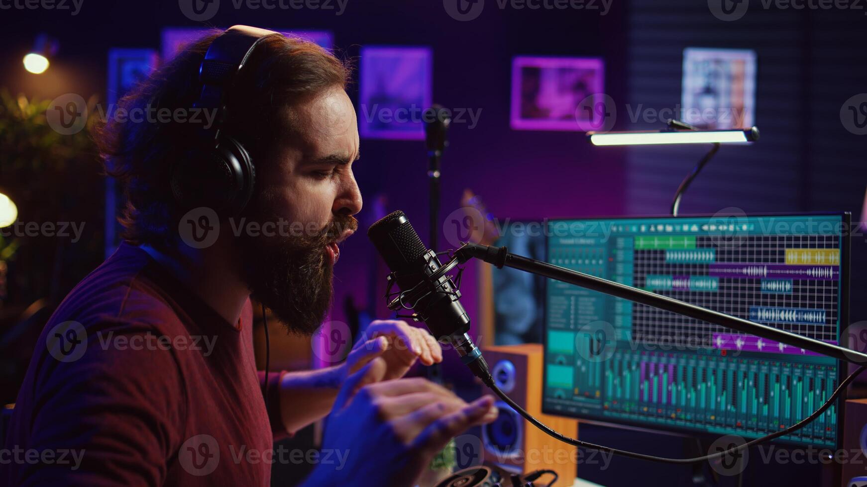 Music producer singing at home studio microphone to record songs, editing and adjusting volume levels in post production. Audio engineer conducts recordings of vocals, mixing console. Camera B. photo