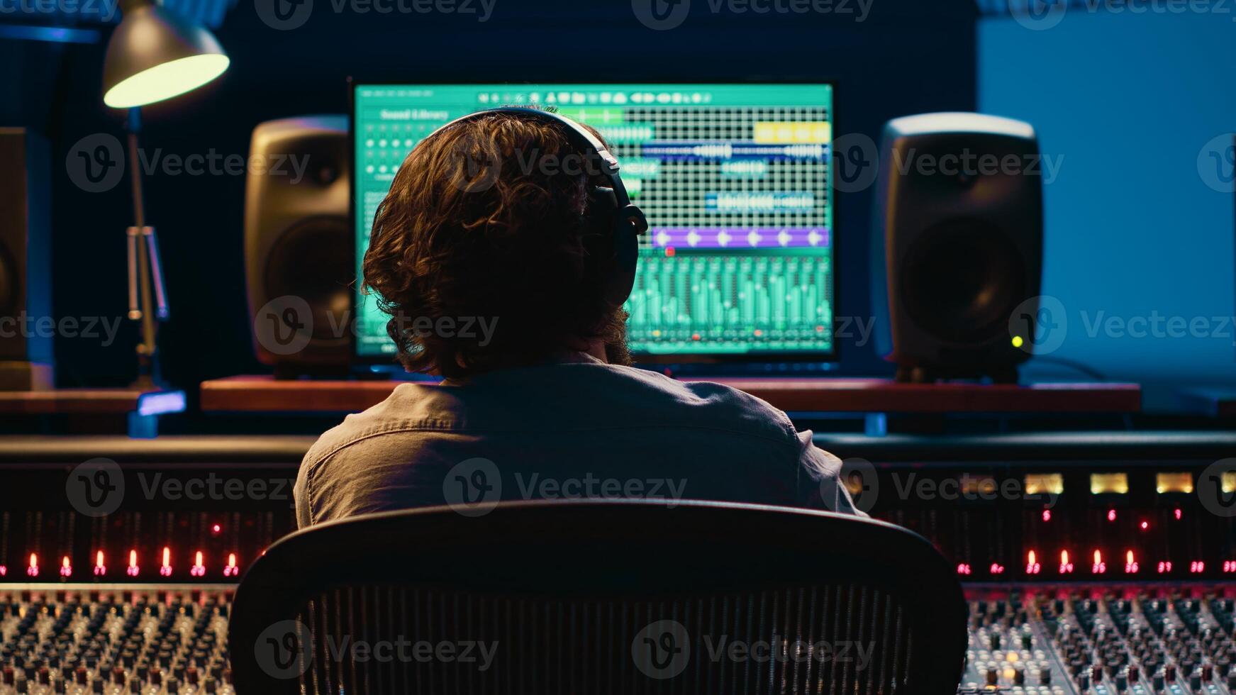 Using audio editing software, sound producer creates tunes and handling technical equipment on a control room dashboard. Technician music producer increases tracks quality. Camera A. photo