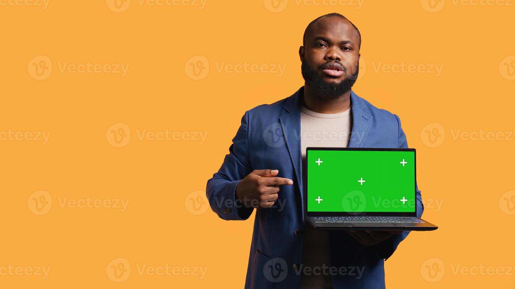 Jolly african american man holding green screen laptop, doing recommendation. Friendly BIPOC person pointing towards mockup notebook, giving positive feedback, studio background, camera B photo