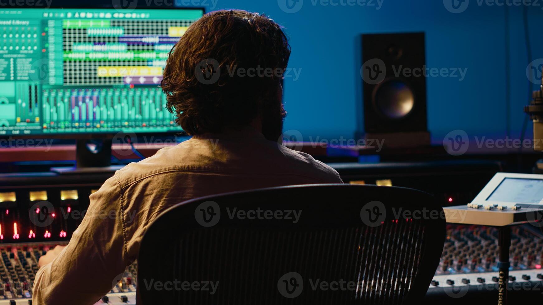 Audio technician working in control room to edit and process tracks, using audio software on pc for music industry post production. Skilled producer creating tunes with mixing console. Camera A. photo